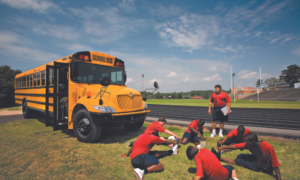 Yellow school bus and soccer players stretching